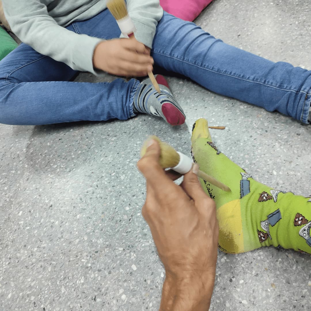 Arteterapeuta en sesión con un niño, ambos sujetan pinceles en la mano