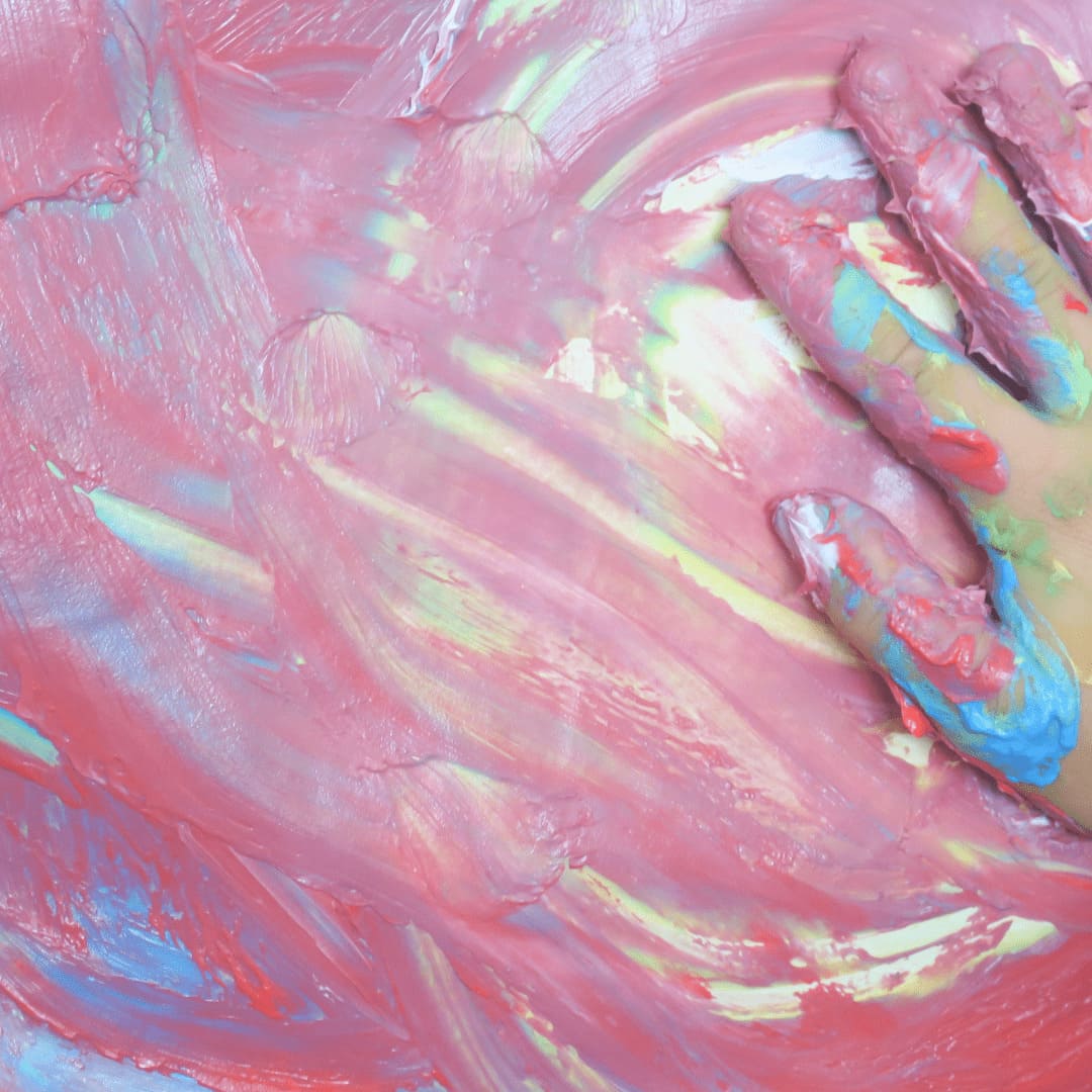 Exploración creativa en la arteterapia, una mano infantil cubierta de pintura.