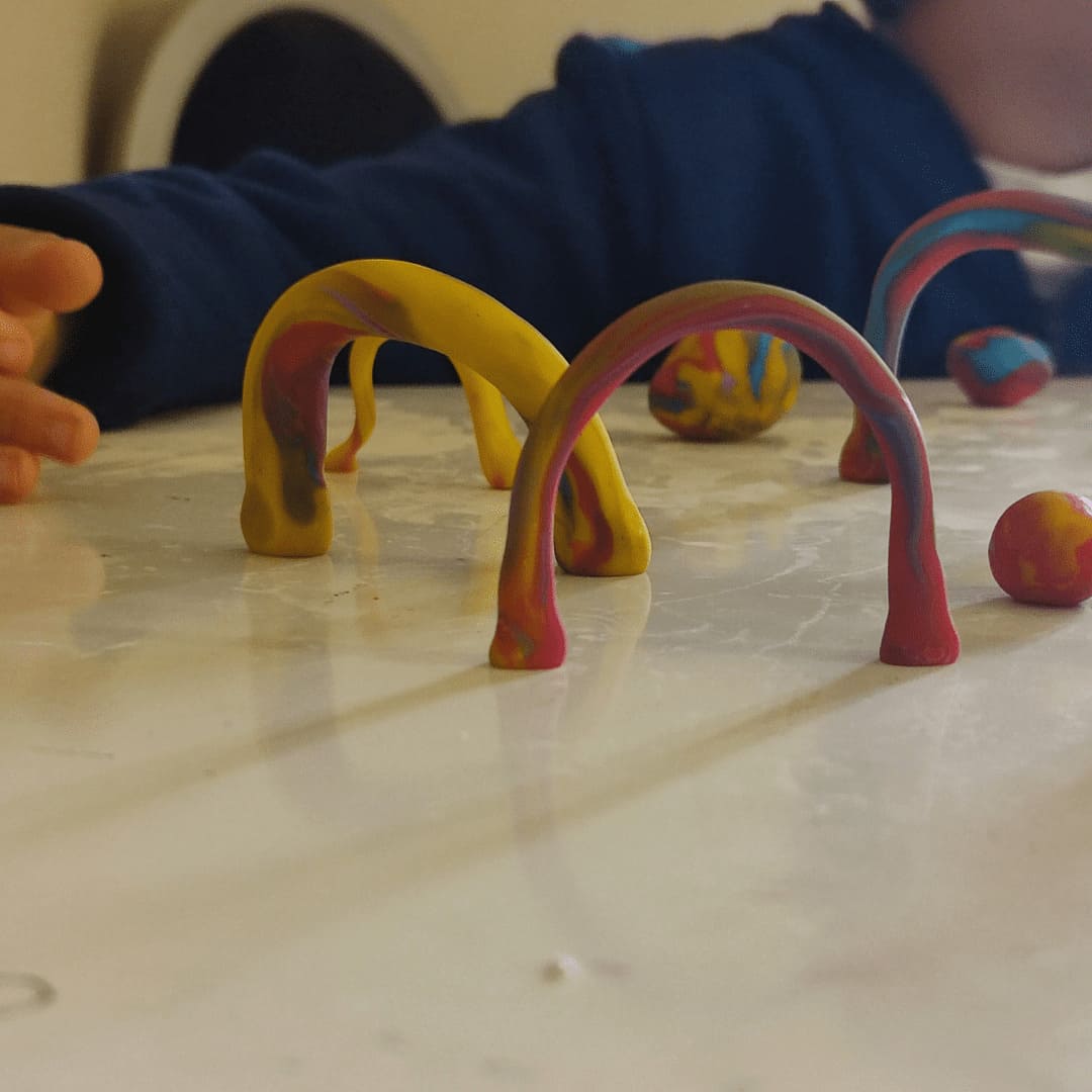 Niño creando arcos con plastilina durante una sesión de arteterapia en la infancia