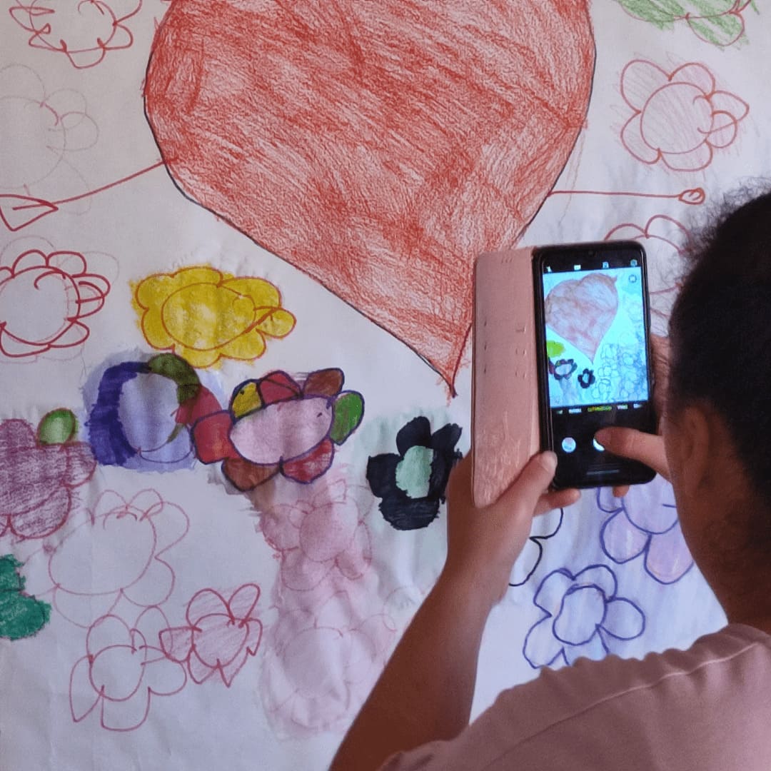 Paciente adolescente de arteterapia fotografiando el resultado de una sesión, se trata de un mural pintado con ceras