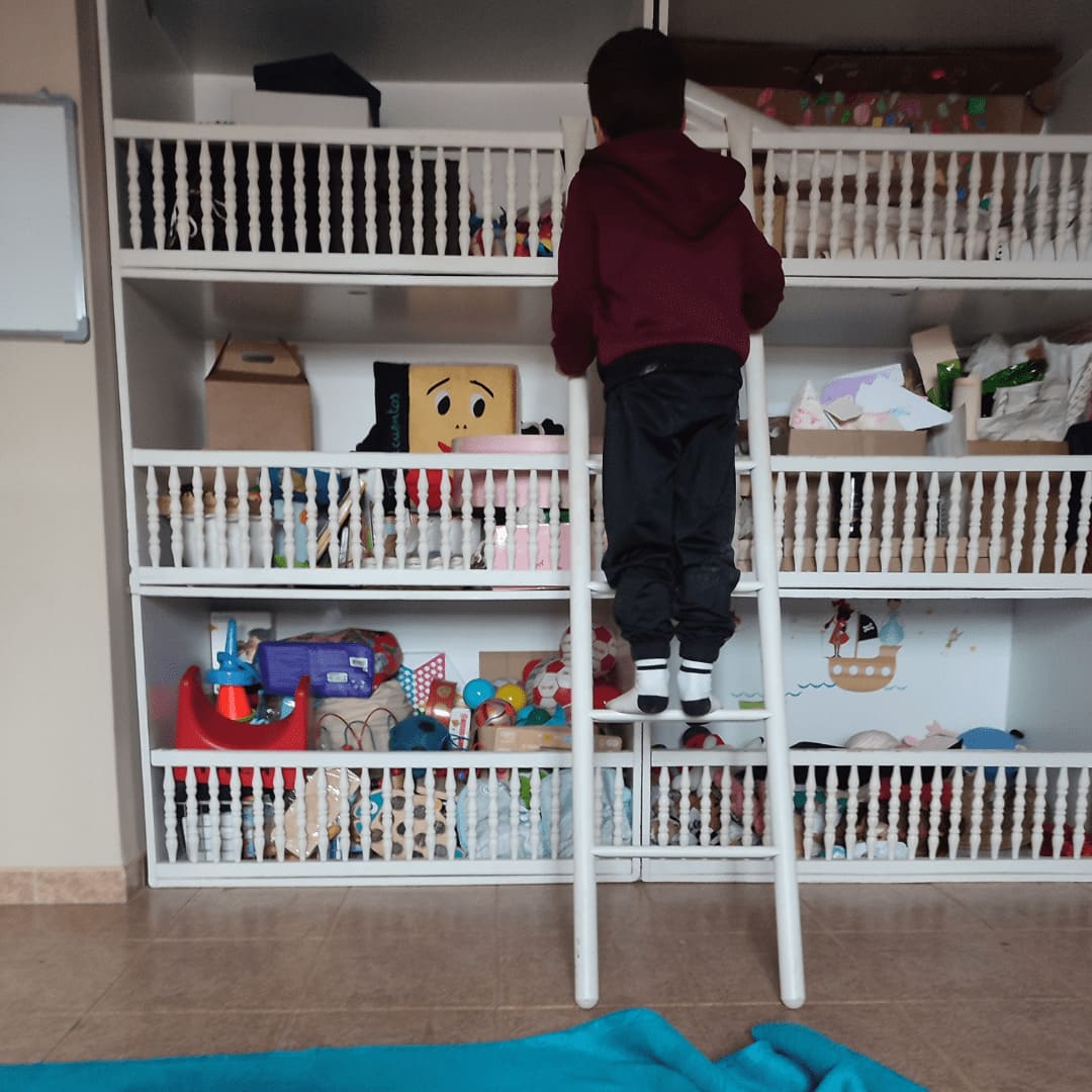 Paciente explorando durante una sesión de arteterapia infantil, vemos a un niño de espaldas subido a una escalera.
