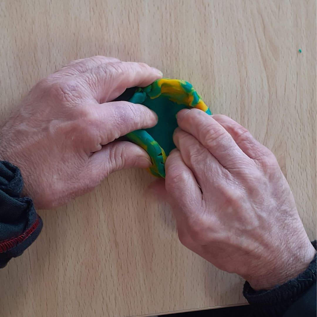 Manos de un paciente adulto en una sesión de arteterapia integrativa, vemos sus manos desde arriba